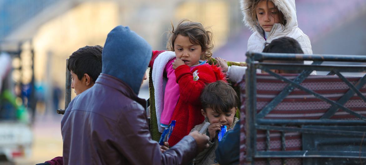 Crianças chegam com suas famílias a um centro de recepção na cidade de Ar-Raqqa, na Síria