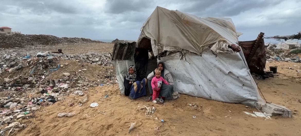 Uma família sentada fora de um abrigo improvisado em Gaza Uma família sentada fora de um abrigo improvisado em Gaza