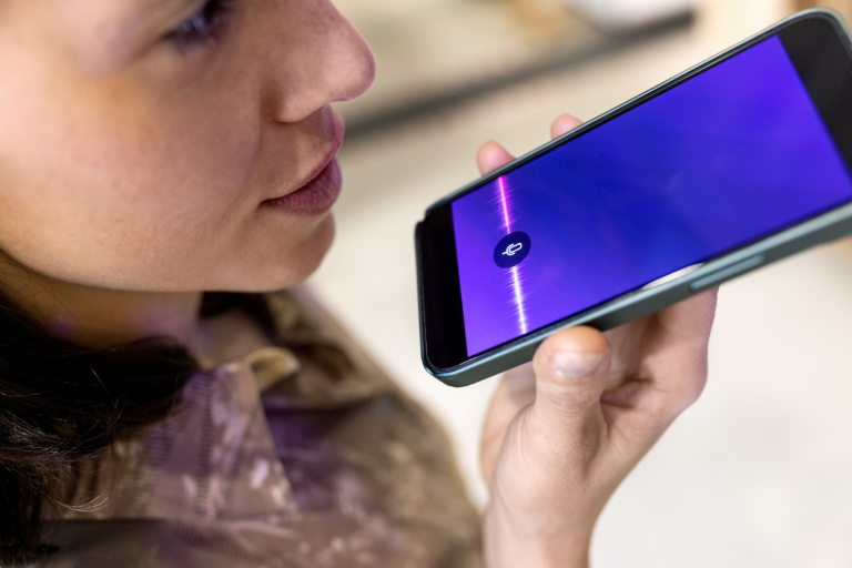 Uma mulher gravando um áudio com o celular