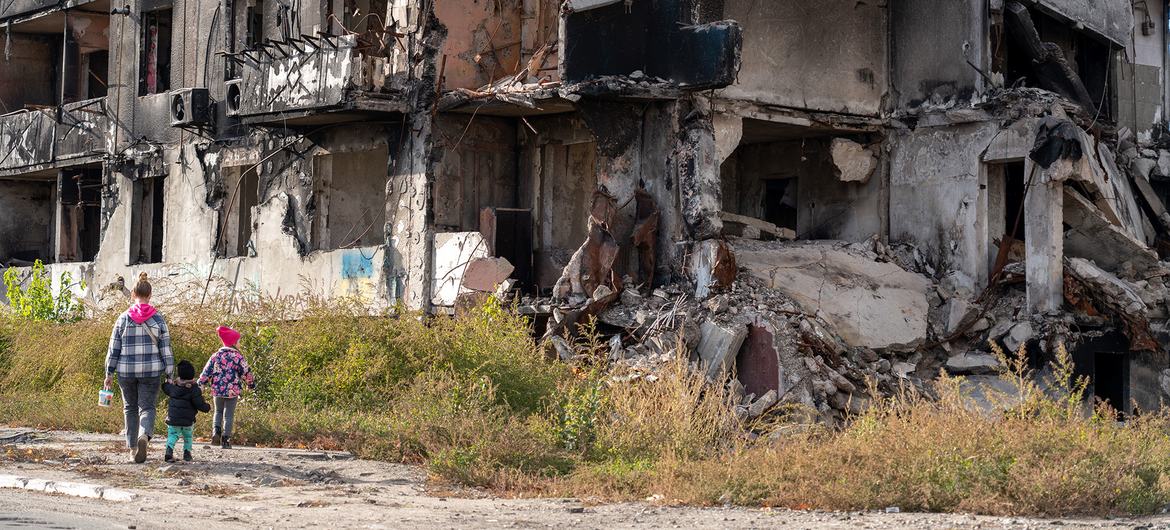 Um adulto e duas crianças passam por um prédio destruído em Borodianka, Ucrânia Prédio destruído em Borodianka