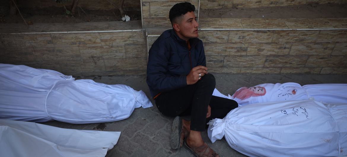 Um homem está sentado entre sacos com cadáveres em Gaza, após novos ataques aéreos
