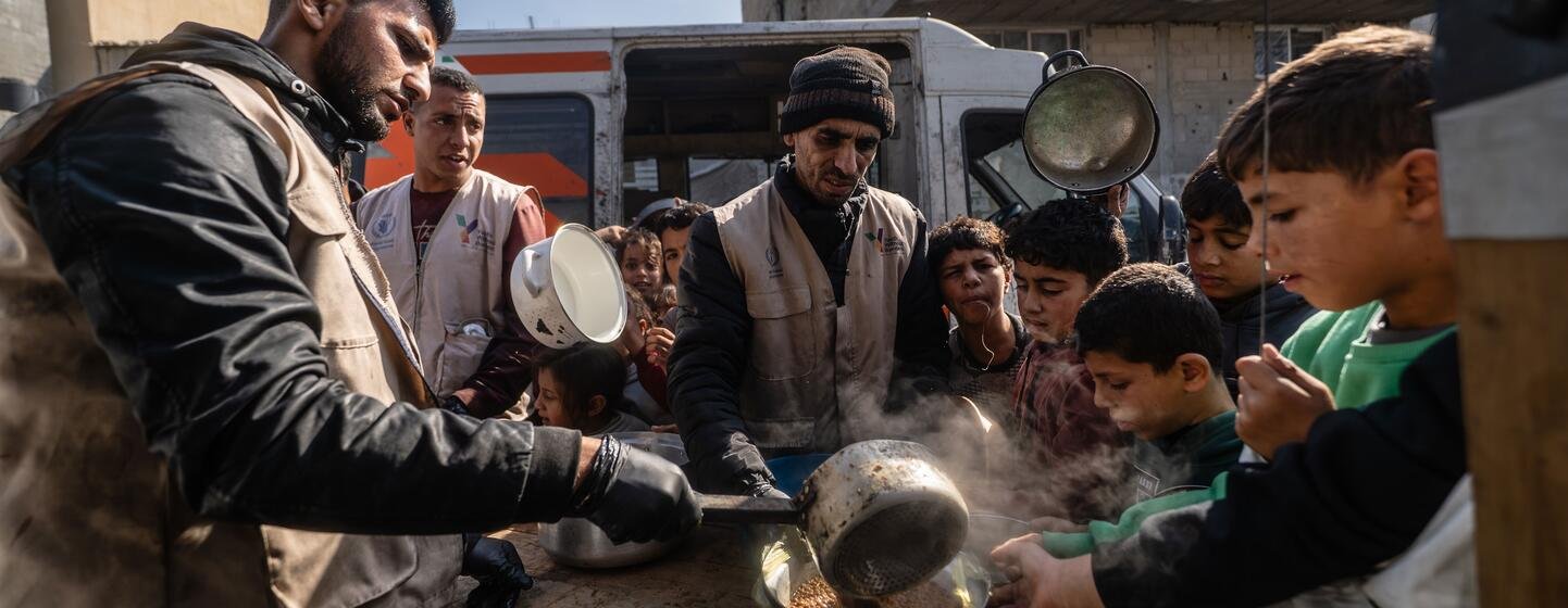Trabalhadores de uma cozinha de refeições quentes apoiada pelo PMA distribuem alimentos em Khan Younis, em Gaza.